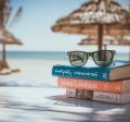 stack of books near beach with umbrellas