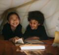 two kids having fun while reading a book