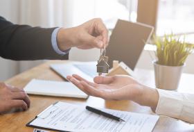Close up of a landload handing house keys to a renter