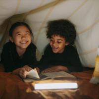 two kids having fun while reading a book