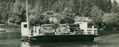 Ferry crosses with cars on the deck.