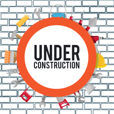 Blue/gray brick wall behind circular sign, ringed by tools, that reads 'UNDER CONSTRUCTION'