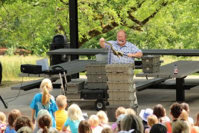 The Reptile Man holds a lizard in front of a crowd of children at the Grove Shelter in Memorial Park