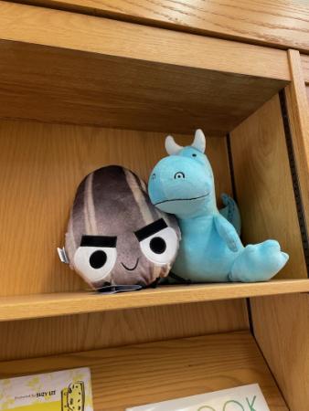 Dragon and Bad Seed hiding on a library shelf