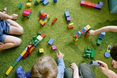 toddlers playing with blocks on green rug