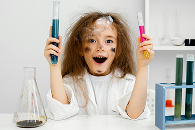 child holding beakers with look of surprise and smudges on their face