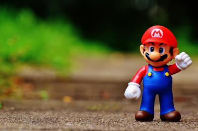 photo of Mario figure standing on the ground with greenery in the background