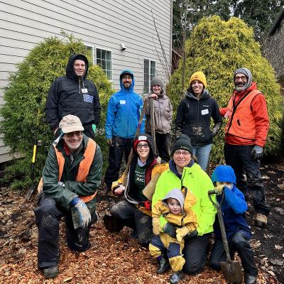 Tree planting volunteers pose near a residence.