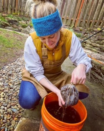 woman making compost tea in orange bucket