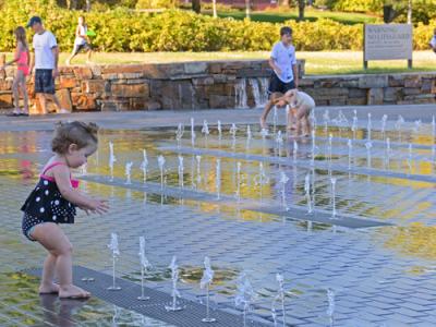 young girl playing in water feature