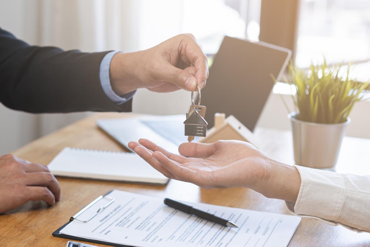 Close up of a landload handing house keys to a renter