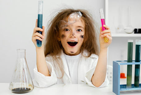 child holding beakers with look of surprise and smudges on their face