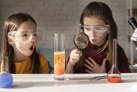 two girls wearing goggles doing science