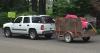 Car with hitched trailer full of bulky waste.